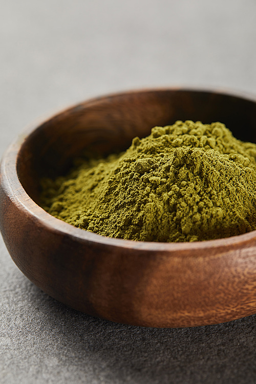 selective focus of green matcha powder in wooden bowl