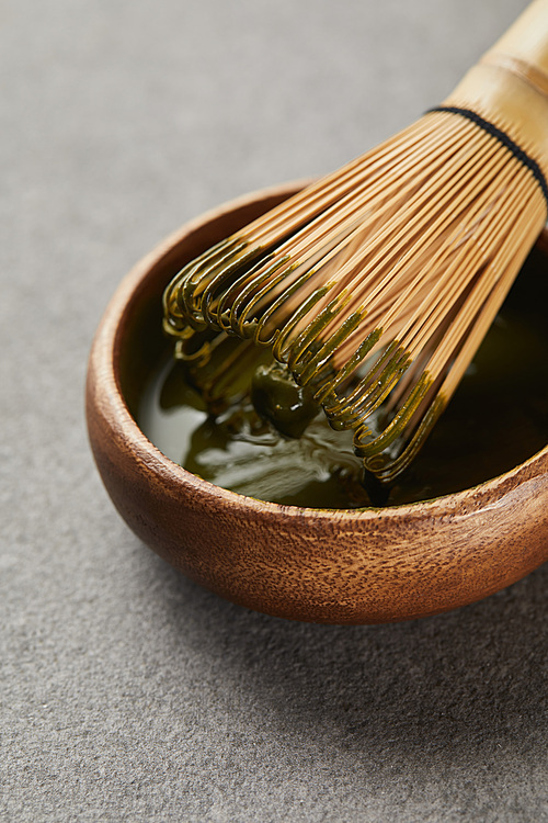 bamboo whisk in wooden bowl with matcha tea