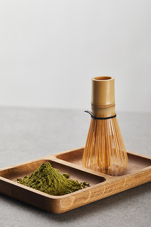 green matcha powder and bamboo whisk on wooden board