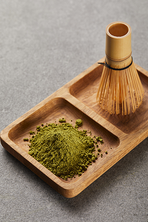 high angle view of green matcha powder and bamboo whisk on wooden board