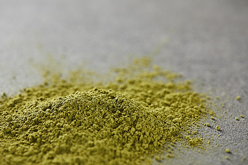 selective focus of green matcha powder on grey table