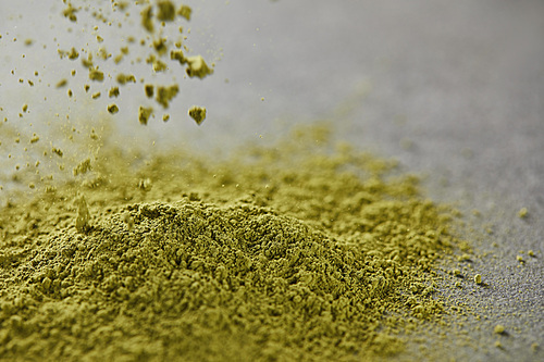selective focus of green matcha powder pouring on table
