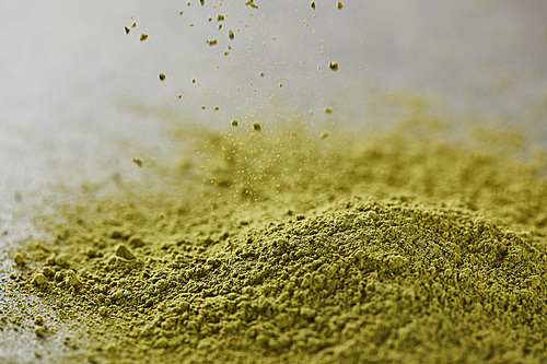 selective focus of green matcha powder pouring on table