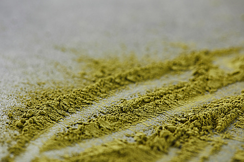 selective focus of green matcha powder on grey table
