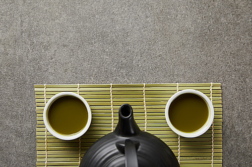 top view of white cups with matcha and 홍차pot on green bamboo table mat