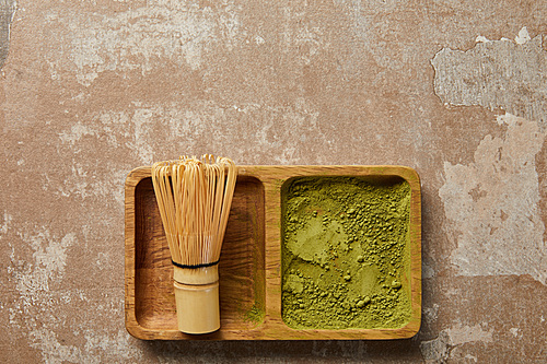 top view of matcha powder and bamboo whisk on wooden board