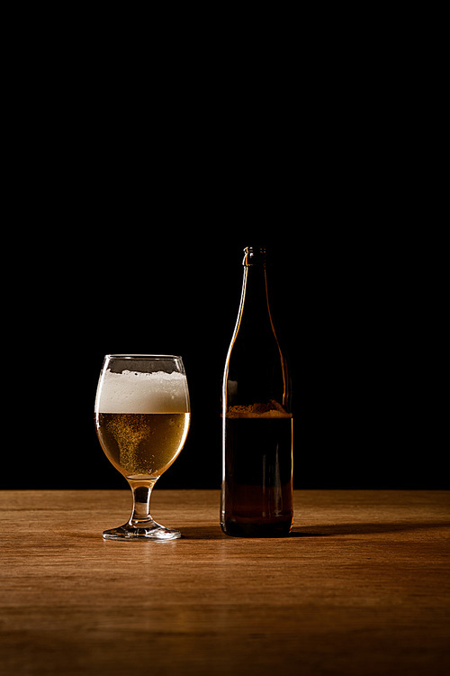 beer in bottle and glass on wooden table isolated on black
