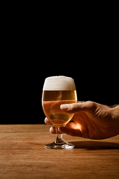 partial view of man holding glass of beer isolated on black