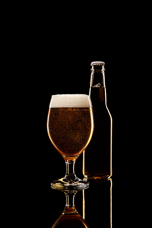 bottle and glass of beer with white foam isolated on black