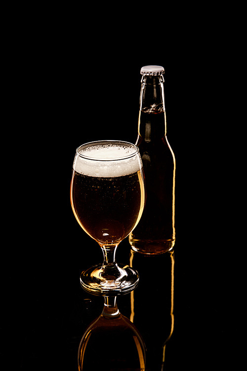bottle and glass of beer with white foam and bubbles isolated on black