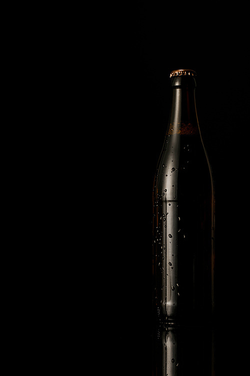 glass bottle of beer with water drops isolated on black