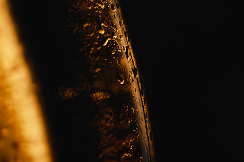 close up view of water drops on glass bottles of beer isolated on black