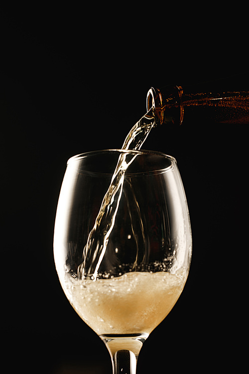 beer flowing from bottle into glass isolated on black