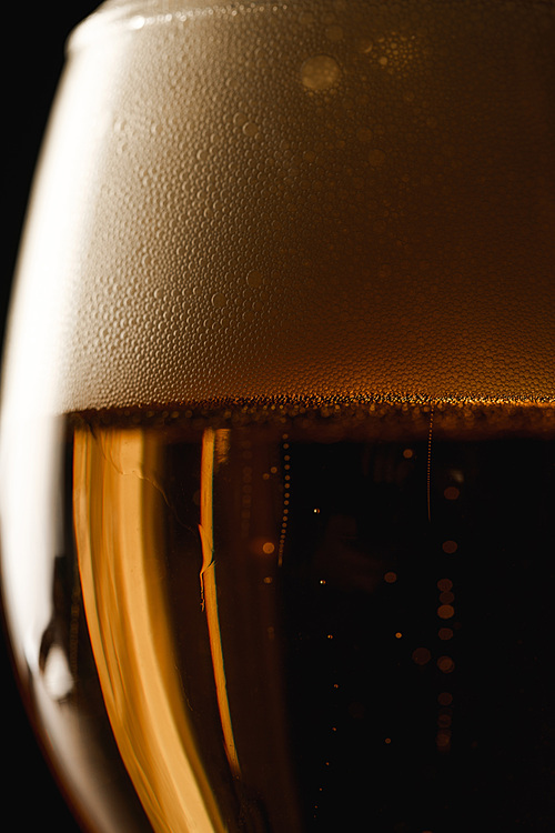 close up view of beer with foam isolated on black