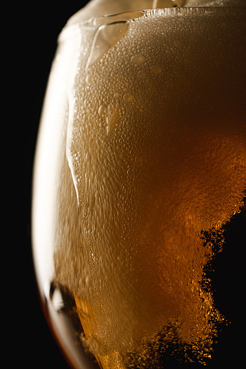 close up view of beer foam in glass isolated on black