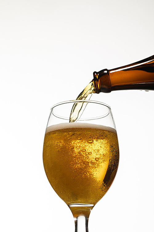 low angle view of fresh beer pouring from bottle into glass isolated on white