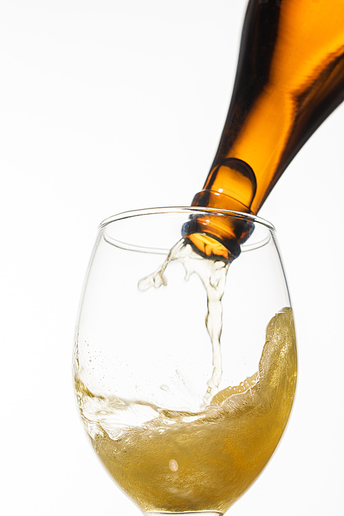 beer pouring from bottle into glass with splash isolated on white
