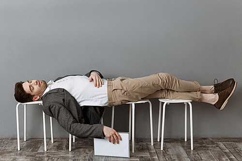 tired businessman with documents sleeping on chairs wile waiting for job interview