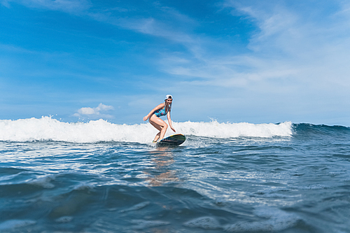 caucasian woman in swimming suit surfing in ocean