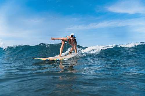 woman in swimming suit and cap surfing in ocean