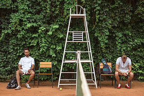 tennis players resting after training on chairs on court