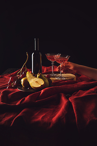 still life with fruits and wine on red drapery on black