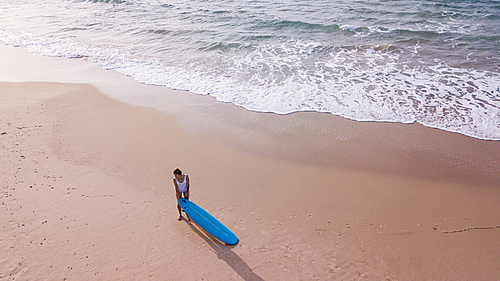 aerial view of young woman in swimsuit with surfboard on sandy beach, Ashdod, Israel