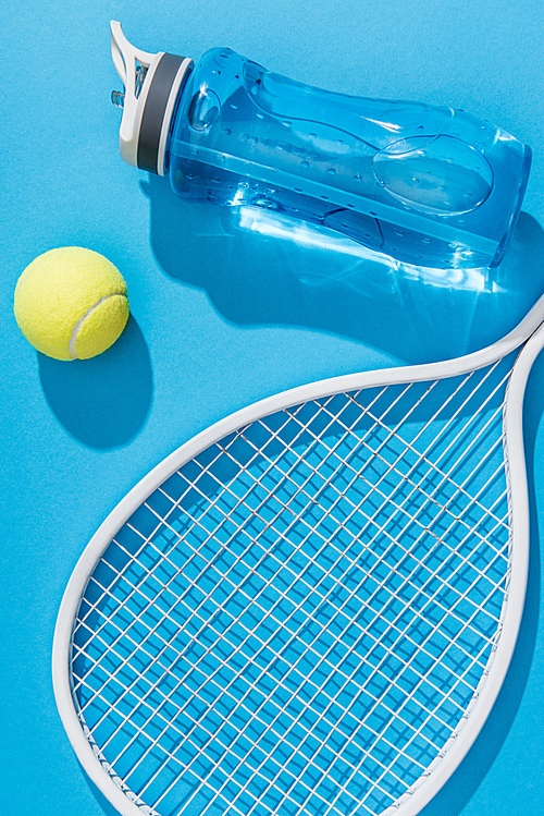 close up view of sportive water bottle and tennis equipment on blue backdrop