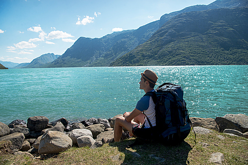 hiker with backpack resting near Gjende lake in Jotunheimen National Park, Norway