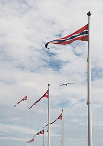 low angle view of norwegian flags against cloudy sky, Hamar, Hedmark, Norway