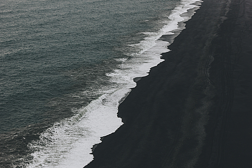 aerial view of coastline with black sand beach near wavy ocean in Vik, Iceland