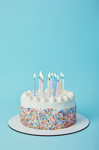 Tasty birthday cake with lighting candles on blue background