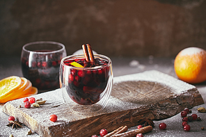 homemade mulled wine with cranberries, orange and cinnamon sticks on wooden stand in kitchen