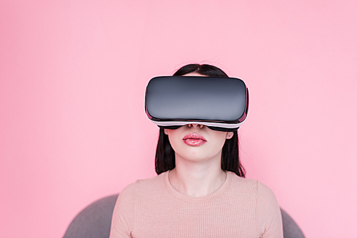 beautiful young woman using virtual reality headset isolated on pink