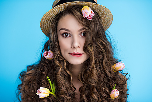 playful young woman in canotier hat with flowers in her long curly hair 