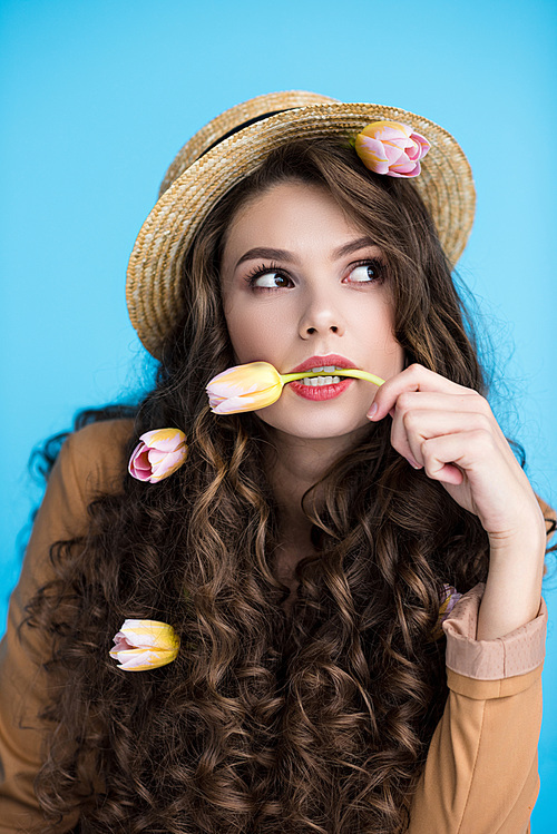 thoughtful young woman in canotier hat with flowers in her long curly hair and mouth