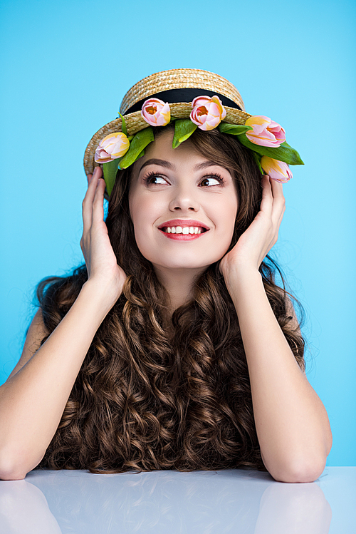 happy young woman in boater hat with beautiful tulips under it