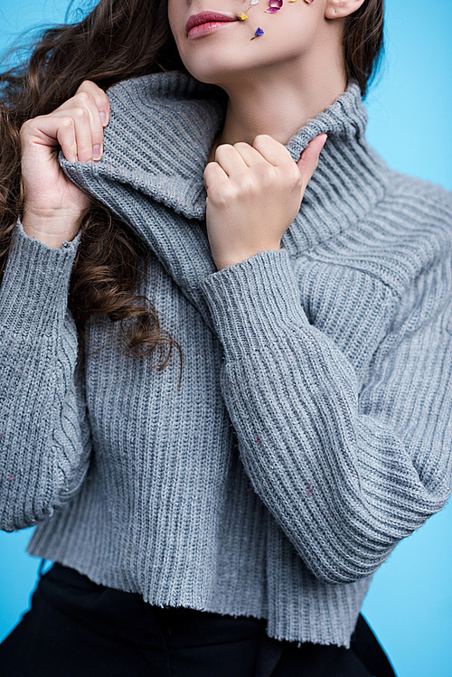 cropped shot of woman stretching neck of stylish sweater isolated on blue