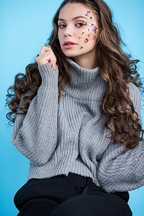 attractive elegant brunette woman with flowers on face  isolated on blue