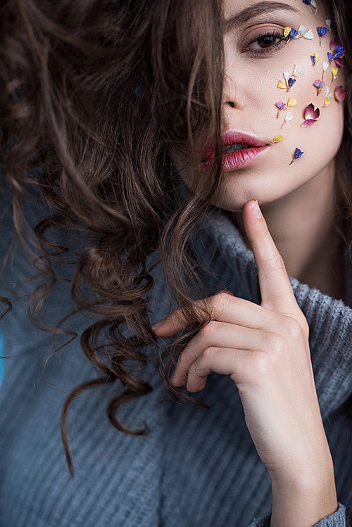 close-up view of sensual brunette woman with flowers on face 