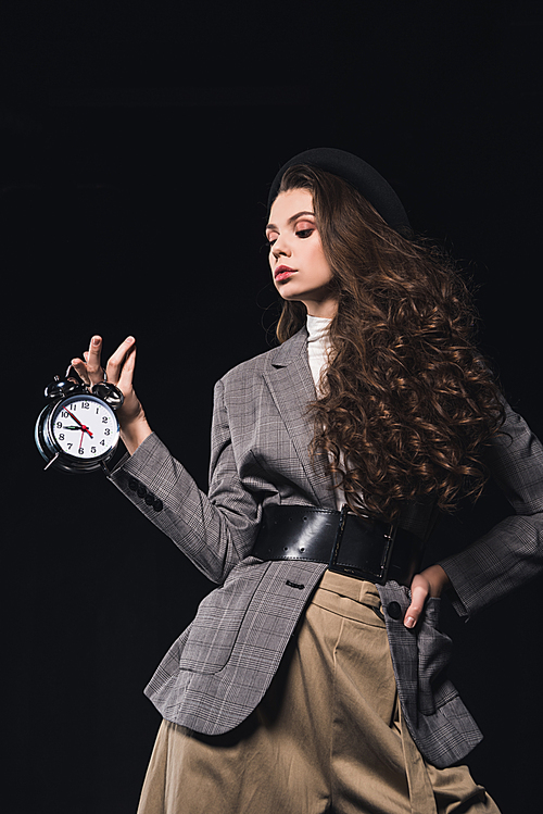 elegant fashionable young woman holding clock isolated on black