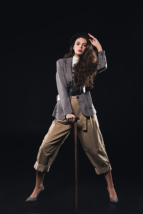 stylish young woman posing with walking stick and  isolated on black