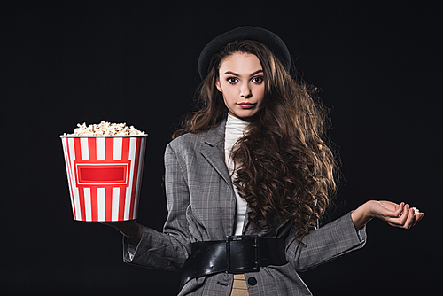 beautiful stylish young woman holding popcorn and  isolated on black