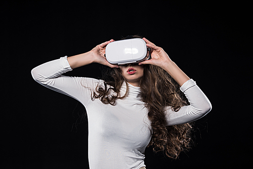 attractive brunette woman using virtual reality headset isolated on black