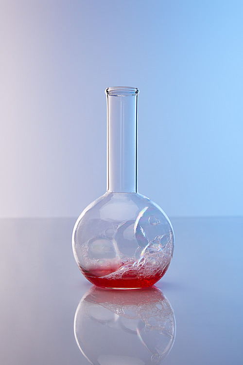 glass flask with colorful red liquid on blue background