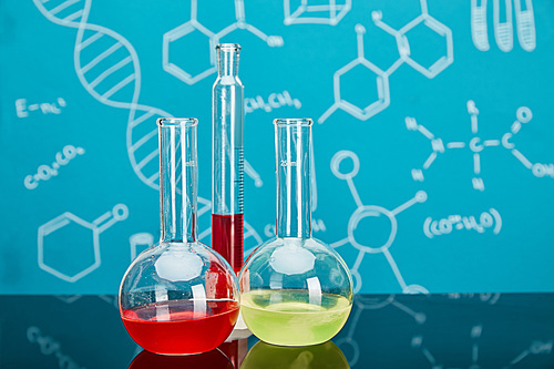 glass test tube and flasks with colorful liquid on blue background with molecular structure