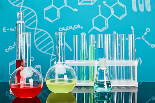 glass test tubes and flasks with colorful liquid on blue background with molecular structure