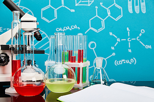 microscope, glass test tubes and flasks with colorful liquid near open copybook on blue background with molecular structure