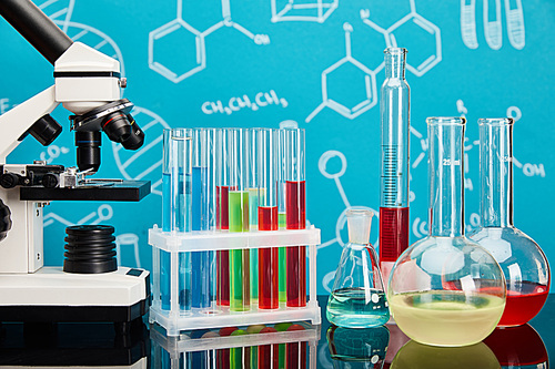 microscope, glass test tubes and flasks with colorful liquid on blue background with molecular structure