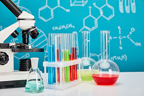 microscope, glass test tubes and flasks with colorful liquid on blue background with molecular structure